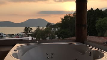 Un jacuzzi con vista a un cuerpo de agua y montañas al fondo.