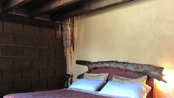 A bed with a striped bedspread, a wooden headboard, and a nightstand with a lamp.