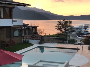 A modern house with a swimming pool, a view of a lake, and mountains in the background.