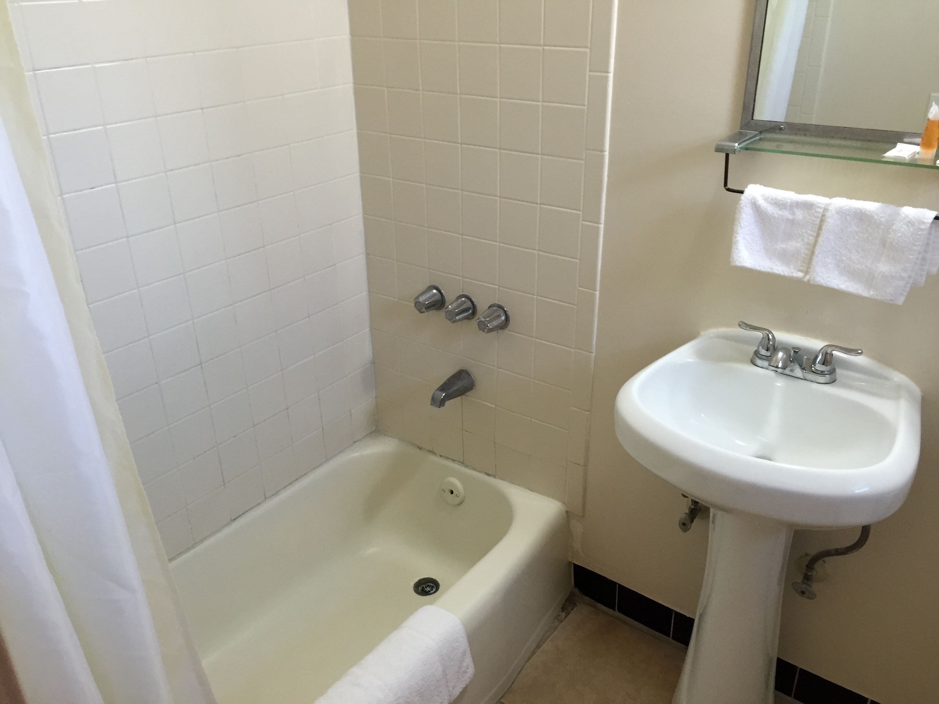 A bathroom with a bathtub, a sink, and a mirror.