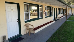 Un bâtiment doté d’un porche couvert, d’une porte portant le numéro « 118 » et d’une rangée de fenêtres aux encadrements verts.