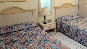 Une chambre avec deux lits, une table de chevet avec une lampe et un téléphone, et un miroir au mur.