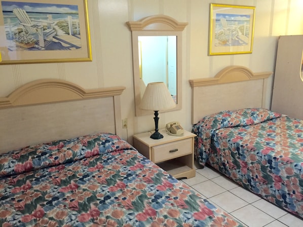 Un dormitorio con dos camas, una mesita de noche con lámpara y teléfono, y un espejo en la pared.