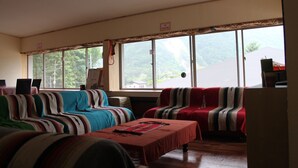 Een kamer met twee banken, een tafel en uitzicht op een berg.
