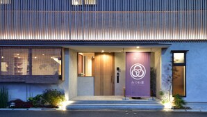 A modern hotel entrance with a wooden door and a purple banner displaying the hotel name.