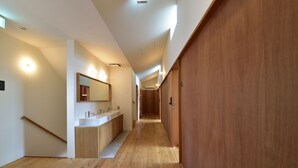 A modern hallway with wooden flooring, a built-in sink area, and a wooden door on the right.