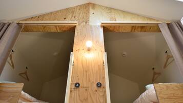 Une pièce dotée d’un plafond en pente et de poutres en bois, comprenant deux lits avec des têtes de lit et un luminaire central.