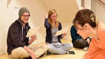 A group of people sitting on the floor in a room with a map of the world on the wall.