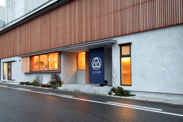A modern building with a wooden facade, a blue entrance door, and a logo on the door. - Hostel Mitsuwaya Osaka (Osaka)