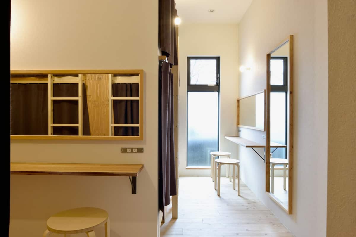 A hallway with a wooden bench, a small stool, and a mirror on the wall.