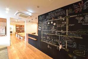 A blackboard with a map and various annotations, including a welcome sign, staff names, and directions to local attractions. - Hostel Mitsuwaya Osaka (Osaka)