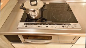 A kitchen with a built-in induction cooktop and a stainless steel pot on it.