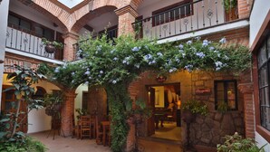 A hotel atrium with a central archway covered in climbing plants, brick walls, and a reception area. - Hotel Casa de Vino (Tequisquiapan)