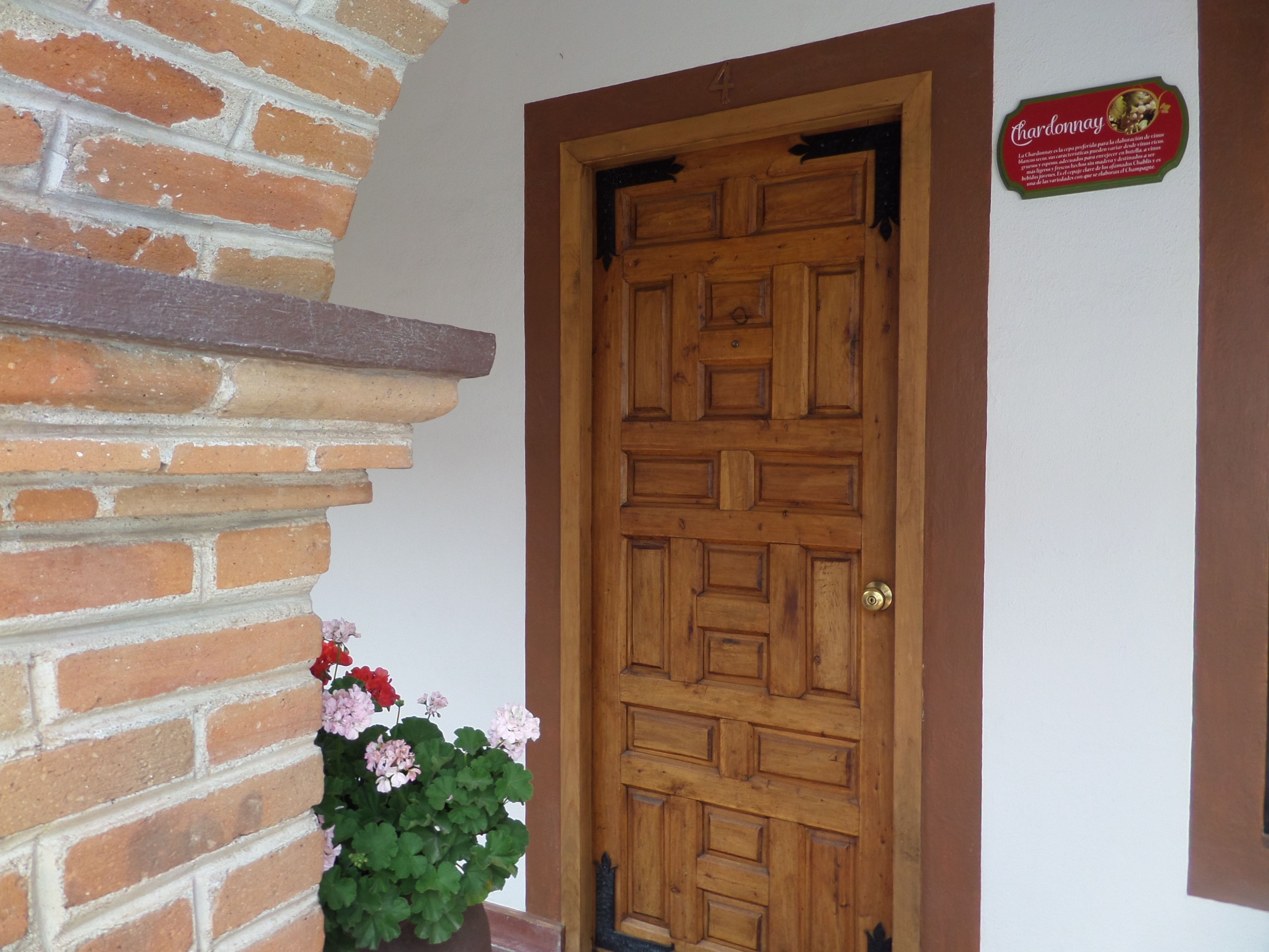 Una porta de fusta amb un mur de maó i un cartell a dalt.