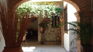 An arched entrance with a reception sign, stone wall, and potted plants. - Hotel Casa de Vino (Tequisquiapan)