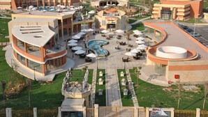 Un complexe hôtelier comprenant plusieurs bâtiments, une piscine extérieure et des espaces de restauration dotés de parasols.