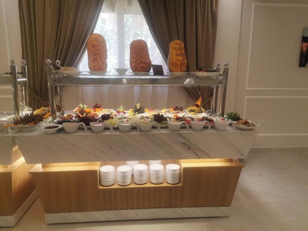 A buffet setup with a variety of food items and a selection of white plates and bowls.