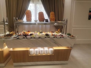 A buffet setup with a variety of food items and a selection of white plates and bowls. - Glorious Hotel (Cairo)