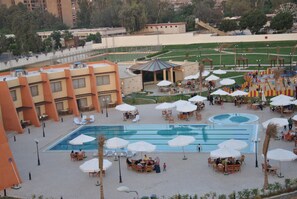 A hotel courtyard with a swimming pool, outdoor seating, and a playground.