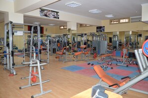A gym with various exercise equipment, mirrors, and a wooden floor.