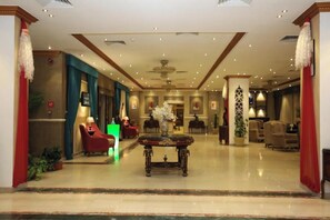 Un vestíbulo de hotel con mostrador de recepción, zona de estar y una mesa decorativa en el centro.