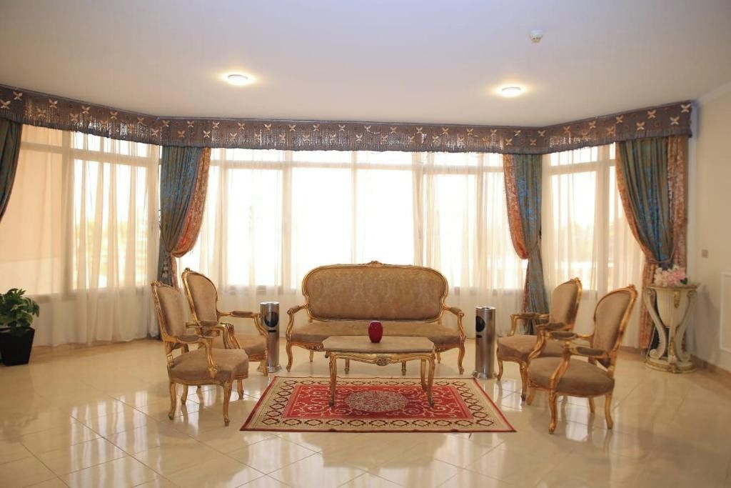 Una habitación con sofá, sillas, una mesita de centro y una alfombra estampada.