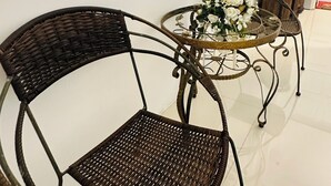 A wicker chair and a small round table with a glass top, accompanied by a metal chair and a wooden cabinet. - J and N Mansion 2 (Patong)