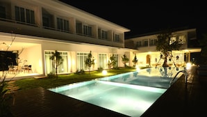 Un hôtel moderne doté d’une piscine, d’un espace extérieur aménagé et de chemins bien éclairés.