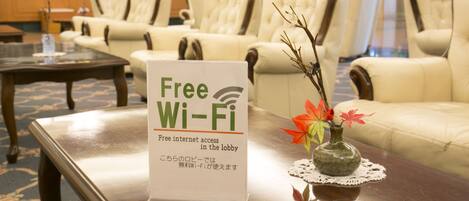 A lobby with a sign offering free Wi-Fi, a vase with autumn leaves, and a seating area with sofas.