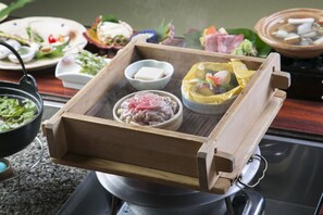 A wooden tray with various food items, including a bowl of meat, a bowl of tofu, and a dish with vegetables.