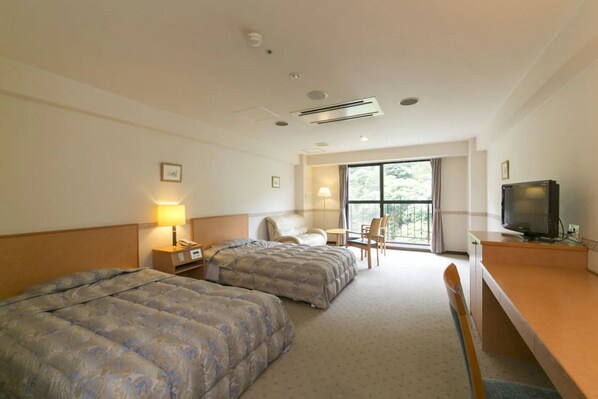 A hotel room with two beds, a desk with a television, a chair, a lamp, and a window with a view of trees. - Okuhida Garden Hotel Yakedake (Takayama)