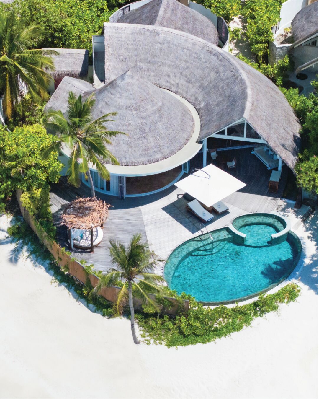 Un complexe hôtelier doté d’un bâtiment circulaire, d’une piscine et de palmiers.