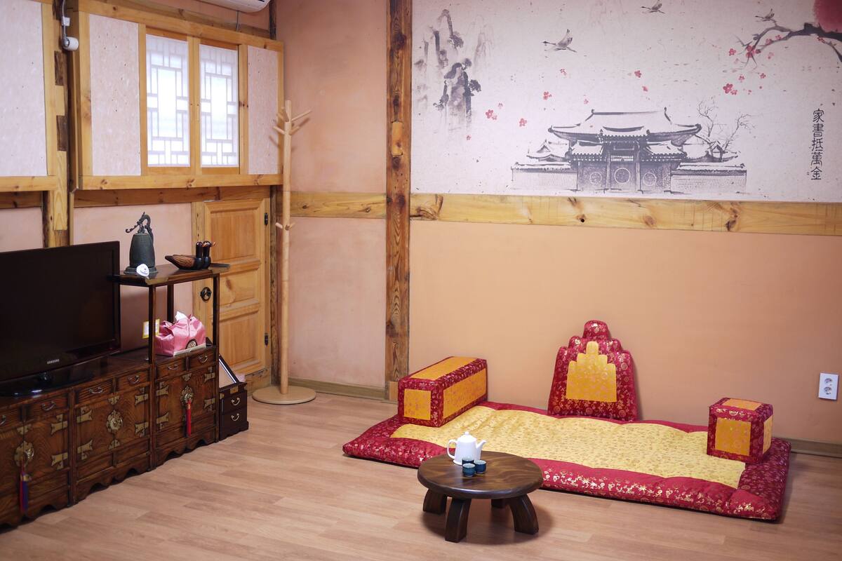 Habitación de estilo tradicional con un aparador de madera, un televisor, un detalle decorativo en la pared con un cuadro y una mesita de madera baja con una tetera.