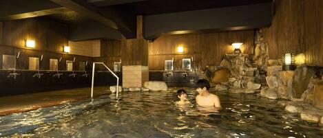 An indoor swimming pool with wooden walls, stone features, and multiple faucets.