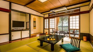 A traditional Japanese room with tatami flooring, a low table, and sliding doors. - Ooedo Onsen Monogatari Terunoyu (Maniwa)