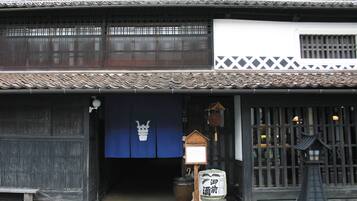 A traditional Japanese building with a dark wooden facade, a tiled roof, and a blue entrance curtain.