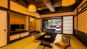 A traditional Japanese room with tatami flooring, a low table with cushions, sliding doors, and a television. - Ooedo Onsen Monogatari Terunoyu (Maniwa)