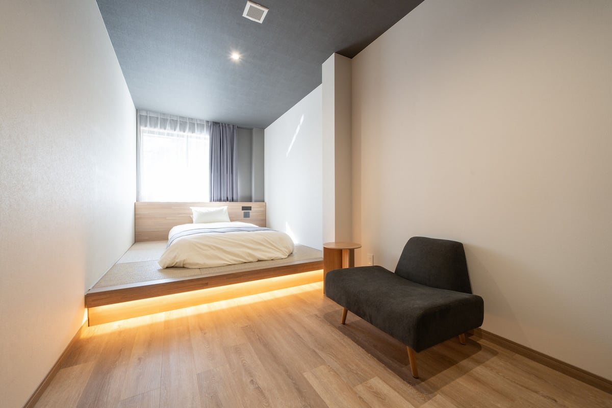 A modern bedroom with a bed, a chair, and a small table.
