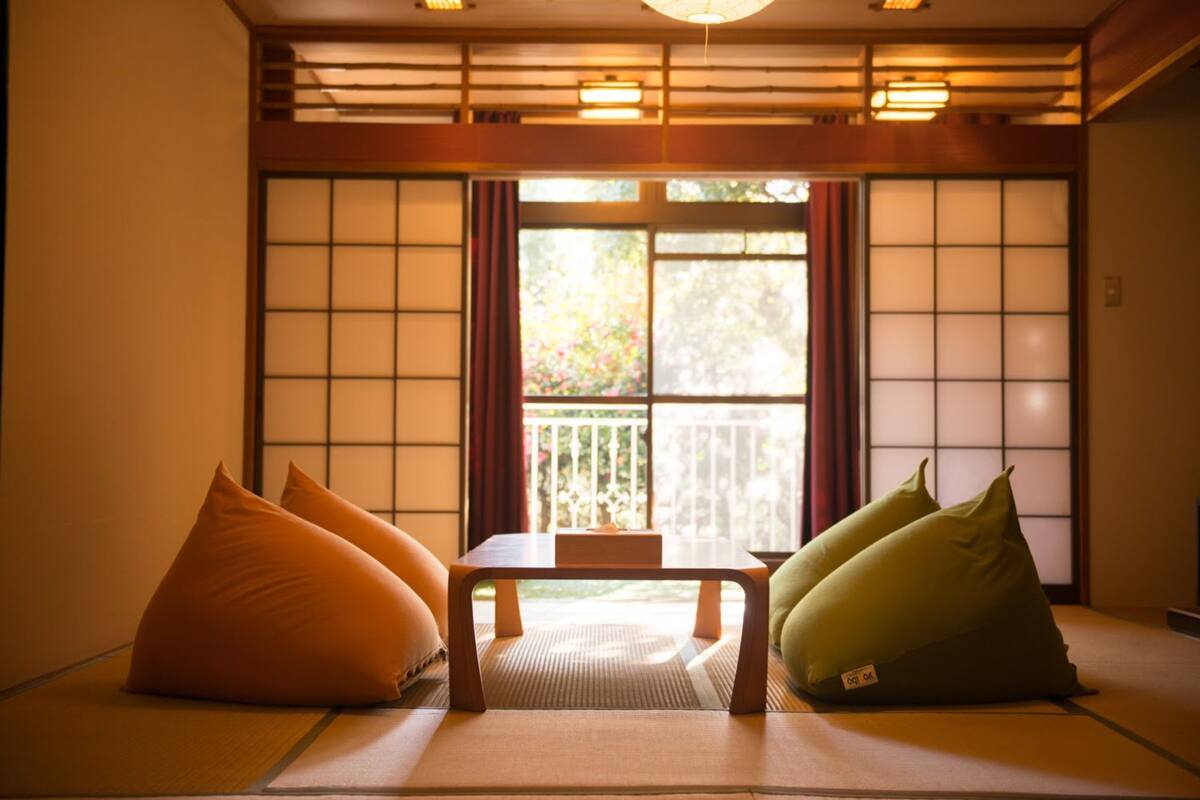 A traditional Japanese room with tatami flooring, a low table, and cushions.
