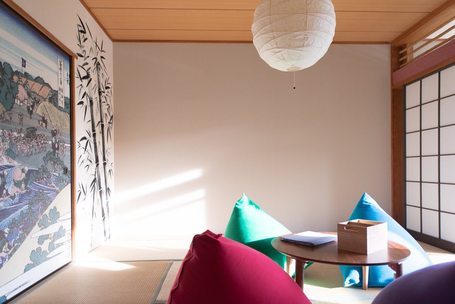Una habitación tradicional japonesa con suelo de tatami, un biombio shoji y un farolillo de papel colgante.