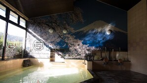 Un onsen japonais traditionnel, orné d’une fresque représentant le mont Fuji, comprenant une source d’eau chaude et un petit bain en bois.