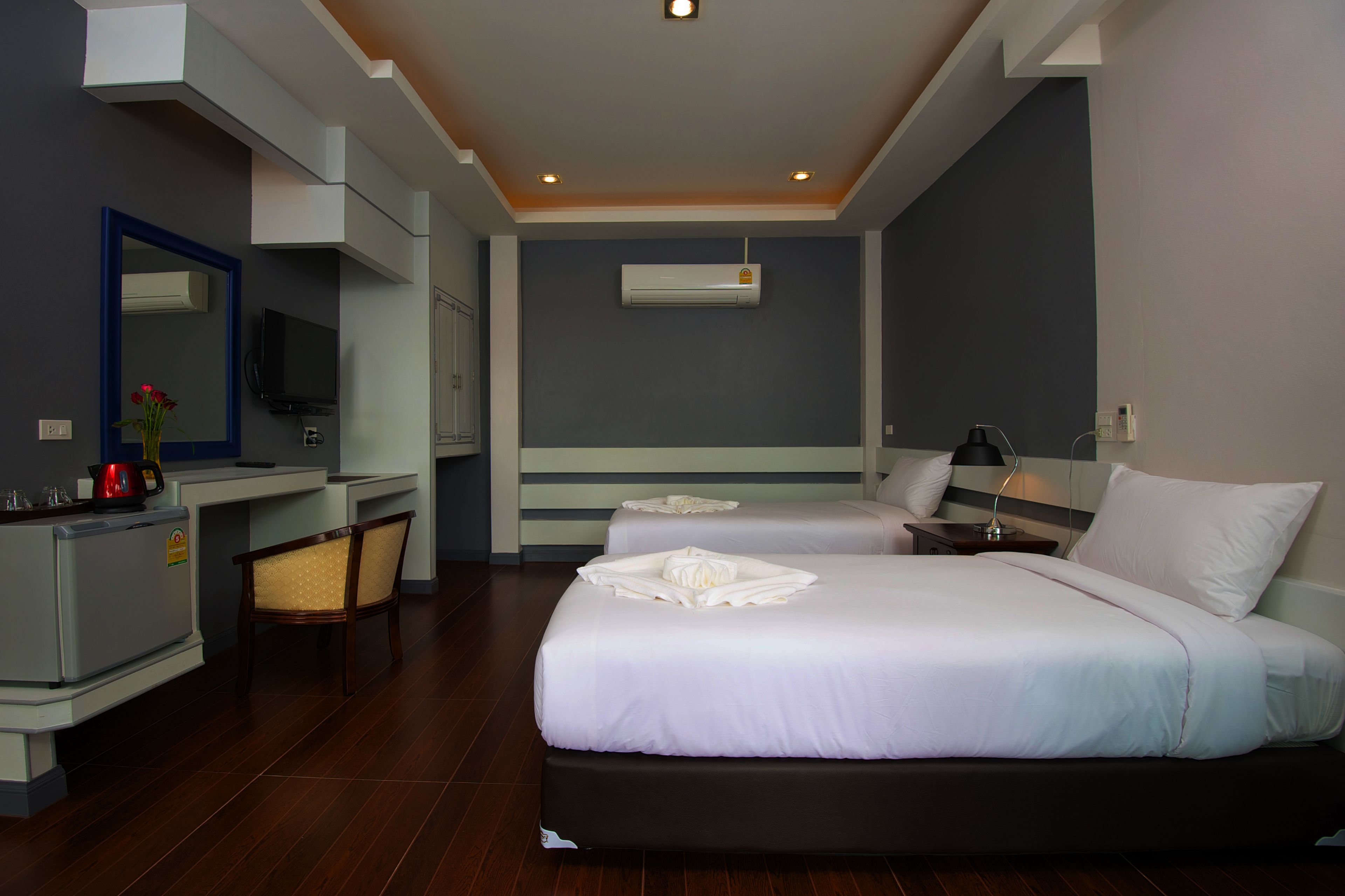 Quarto de hotel com duas camas, uma escrivaninha, uma cadeira, uma televisão e um aparelho de ar condicionado.
