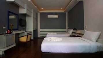 Quarto de hotel com duas camas, uma escrivaninha, uma cadeira, uma televisão e um aparelho de ar condicionado.