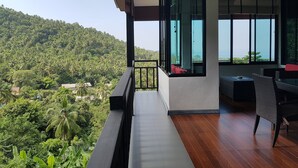 A balcony with a view of a lush green hillside and the ocean.