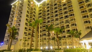 A multi-story hotel with balconies, palm trees, and a well-lit exterior. - Extremeli Suites (Parañaque)