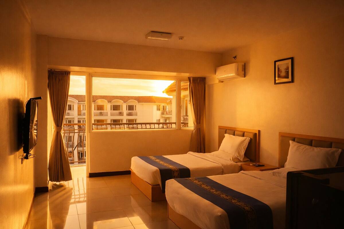 A hotel room with two beds, a TV, a window with curtains, and an air conditioning unit.
