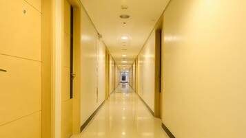 Corredor longo e estreito de hotel, com portas em ambos os lados, que se estende até o final.