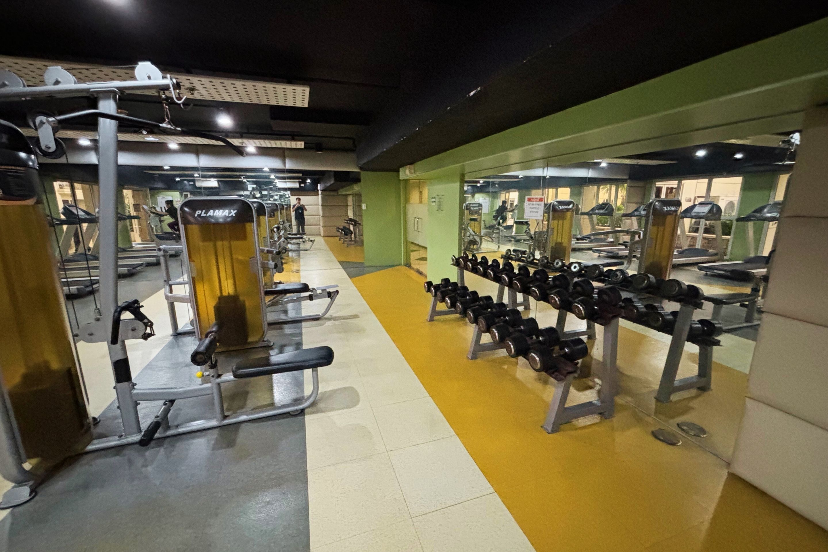A gym with various exercise equipment, including treadmills, weight machines, and dumbbells.