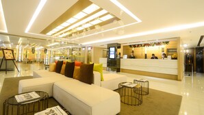 A modern hotel lobby with a reception desk, seating area, and a large window. - Extremeli Suites (Parañaque)