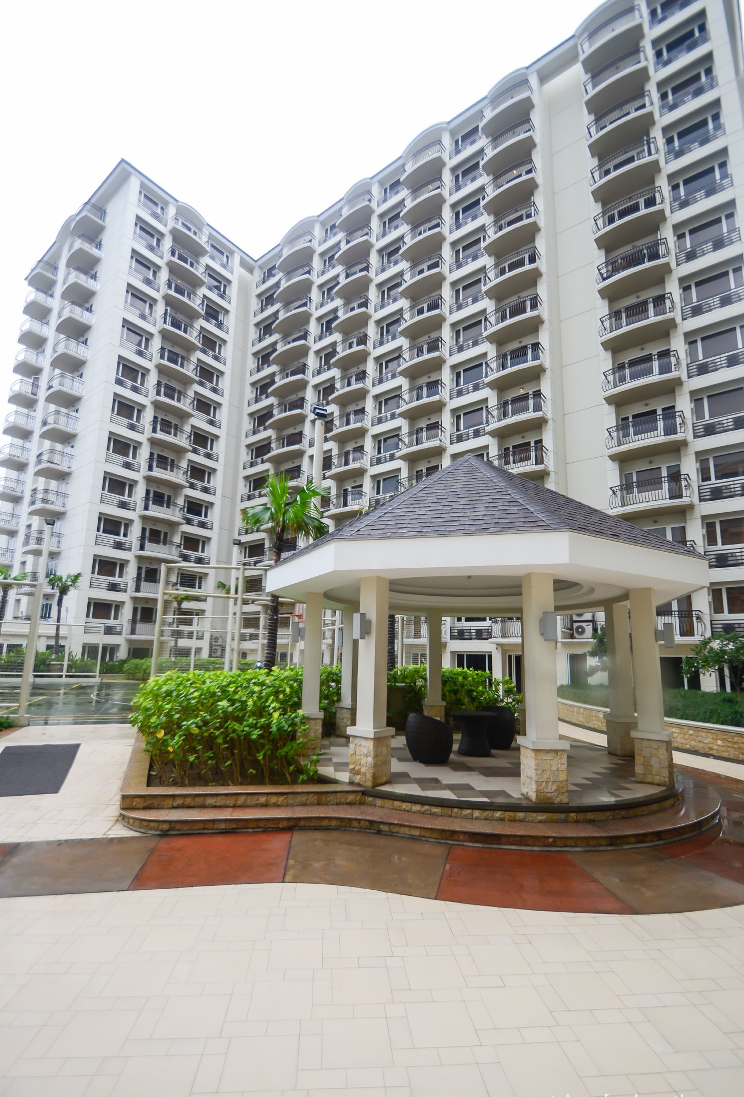 A multi-story residential building with balconies and a central courtyard with a gazebo.